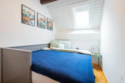 a small bedroom with a blue bed and a window at Misty May Apartment in Bovec