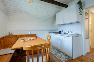 a kitchen with a wooden table and a kitchen with white cabinets at Misty May Apartment in Bovec