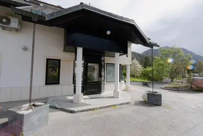 a building with a black awning in a parking lot at ALPEART GOZD MARTULJEK HOLIDAY unit in Kranjska Gora
