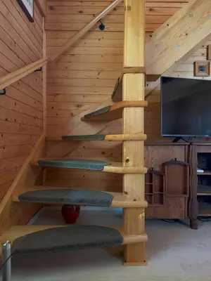 a wooden staircase in a log cabin with a tv at Počitniška hiša z dvema spalnicama Sauna & Jacuzzi in Gorica pri Slivnici