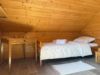 a bedroom with two beds and a desk in a log cabin at Počitniška hiša z dvema spalnicama Sauna & Jacuzzi in Gorica pri Slivnici