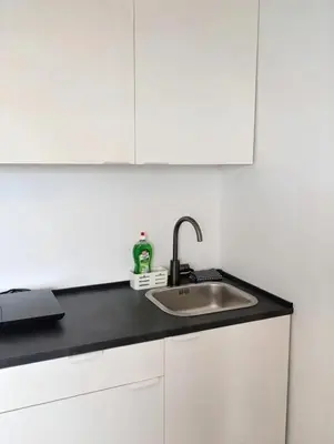 a kitchen counter with a sink and white cabinets at Renovated Apartment for Four in Ljubljana