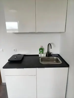 a kitchen counter with a sink and white cabinets at Renovated Apartment for Four in Ljubljana