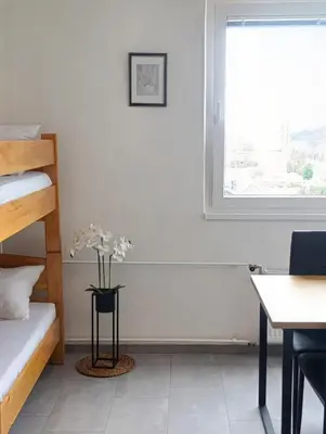 a bedroom with a bed and a desk and a window at Renovated Apartment for Four in Ljubljana