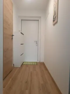 an empty room with a white door and a wooden floor at CoCo Apartment in Ljubljana