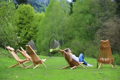 a woman sitting in a chair in a field at Sunset Valley Apartments and Rooms in Bohinj