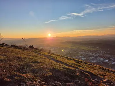a group of people sitting on a hill watching the sunset at Gala Lenassi in Kamnik
