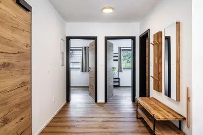 a hallway with white walls and wooden floors and a wooden bench at Family and Friends Apartments Bled in Spodnje Gorje