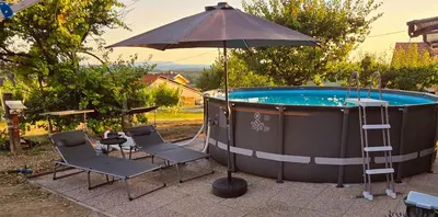 a hot tub with two chairs and an umbrella at Apartma Martin in Miklavž pri Ormožu