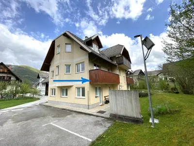 a building with a blue arrow on it in a parking lot at Bee Apartment in Bohinj