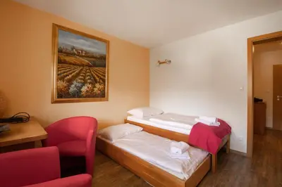 a room with two beds and a chair and a painting at Bee Apartment in Bohinj