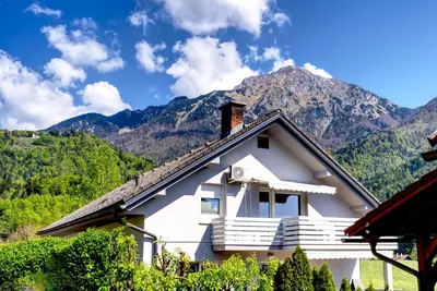 a white house with a mountain in the background at Apartma Storžič in Preddvor