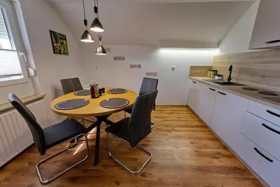 a small kitchen with a wooden table and black chairs at Apartma Storžič in Preddvor
