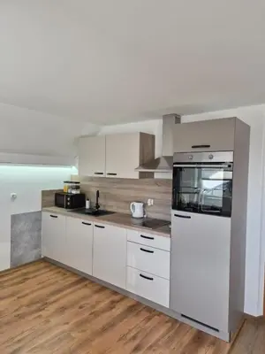 a kitchen with white appliances and wooden floors at Apartma Storžič in Preddvor