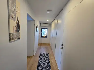 a hallway with white walls and a rug on the floor at Nova Nest from Granite Getaways in Nova Gorica