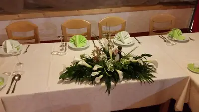 a table with a white table cloth with a vase of flowers at Gostilna Stara Pošta in Pucaie