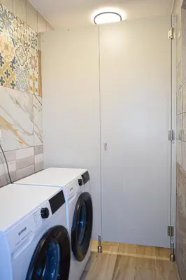 a washing machine in a laundry room with a door at Grajski kamp - pitch your own tent in Kočevje