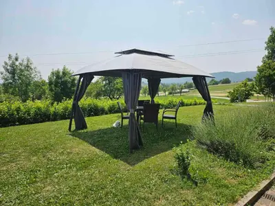 a table and chairs under an umbrella in the grass at Stars Apartments in nature in Postojna