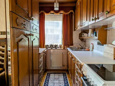 a kitchen with wooden cabinets and a large refrigerator at Apartma Rustika in Bled