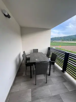 a table and chairs on a balcony with a view of a field at Apartmaji Baznik Čatež in Brežice