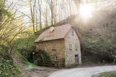 a small stone house in the middle of a road at Old mill in Štore