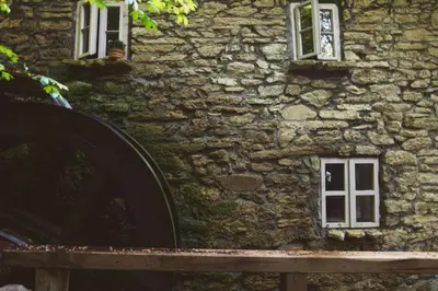 a stone building with two windows and a wooden bench at Old mill in Štore