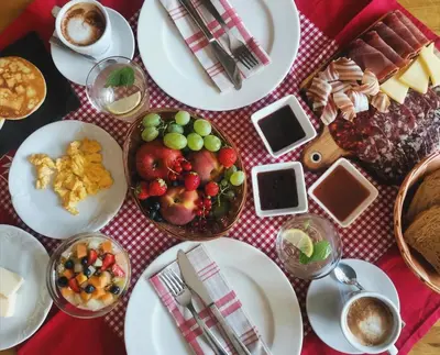 a table with plates of food on a red and white table cloth at Farm Stay Peternelj in Ilirska Bistrica