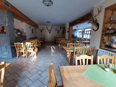 an empty restaurant with wooden tables and chairs at Farm Stay Peternelj in Ilirska Bistrica