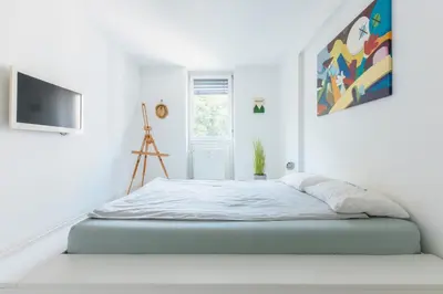 a white bedroom with a bed and a tv at Gatsby's Place in Ljubljana