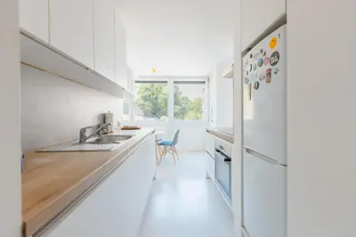 a white kitchen with a sink and a refrigerator at Gatsby's Place in Ljubljana