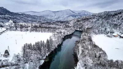 an aerial view of a river with snow covered mountains at Glamping Avantura- a natural getaway by the Kolpa River in Kostel