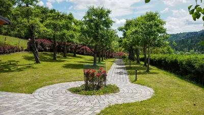 a walkway in a park with flowers and trees at Glamping Avantura- a natural getaway by the Kolpa River in Kostel