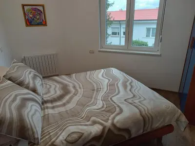 an unmade bed in a bedroom with a window at Apartma Mjrka in Dobrovo