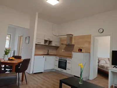 a kitchen with white cabinets and a table and a dining room at Apartma Mjrka in Dobrovo