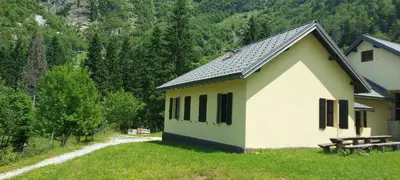 a building with a picnic table in the grass at Dom dr Klementa Juga v Lepeni in Soča