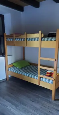a wooden bunk bed with a green pillow on it at Dom dr Klementa Juga v Lepeni in Soča