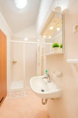a white bathroom with a sink and a shower at Hiša Vanda in Dobrovo