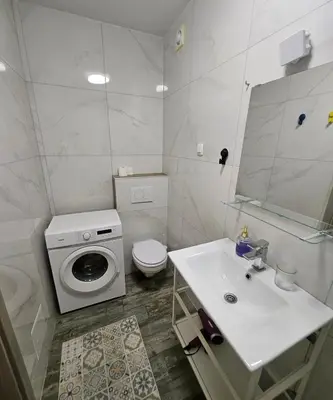 a bathroom with a sink and a washing machine at Apartman min & Ljubljana in Ljubljana