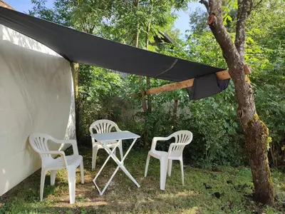 a table and two chairs under a black canopy at Rustic glamping on a farm in Radovljica