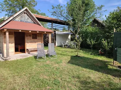 a house with two chairs sitting in the yard at Rustic glamping on a farm in Radovljica