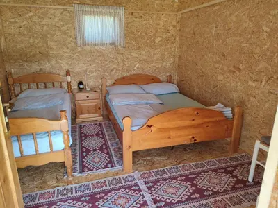 a bedroom with two beds and a table and a window at Rustic glamping on a farm in Radovljica