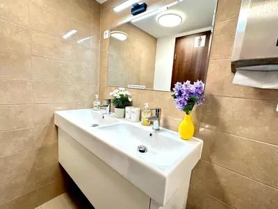 a bathroom with a white sink with flowers in a yellow vase at Rookos rooms in Ljubljana