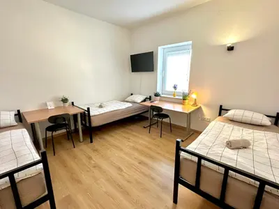 a room with two beds and a desk and a window at Rookos rooms in Ljubljana