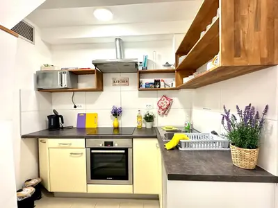 a small kitchen with yellow cabinets and a black counter top at Rookos rooms in Ljubljana