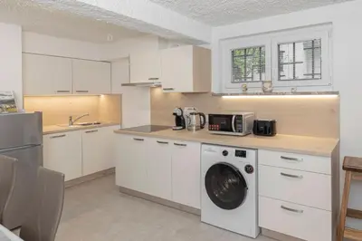 a kitchen with white cabinets and a washer at Serenity Apartment Bled - New, Stylish, Near Lake in Bled