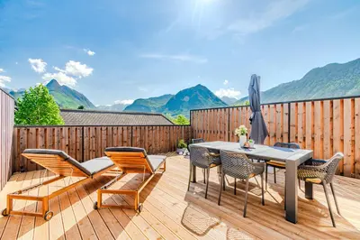 a patio with a table and chairs on a wooden deck at Skalja Apartment in Bovec