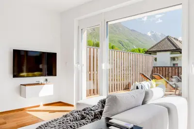 a living room with a white couch and a large window at Skalja Apartment in Bovec