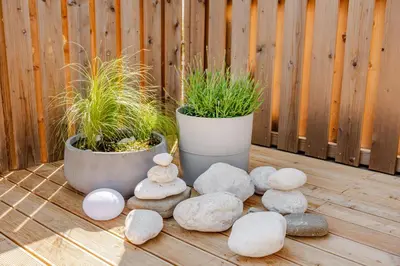 two potted plants and rocks on a wooden deck at Skalja Apartment in Bovec