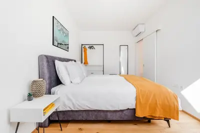 a white bedroom with a large bed and a white table at Skalja Apartment in Bovec