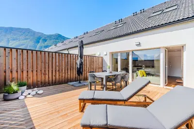 a deck with a table and chairs and an umbrella at Skalja Apartment in Bovec